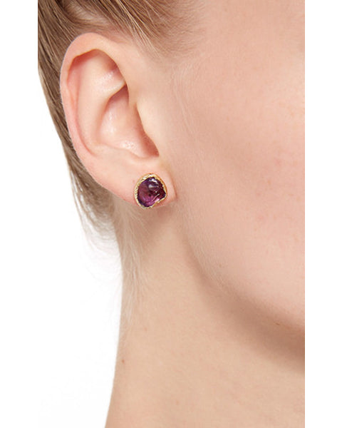 Close-up view of model wearing a Natalie Dissel raw natural Amethyst  18K gold stud earring set in an organic bezel, Moda Operandi edit.
