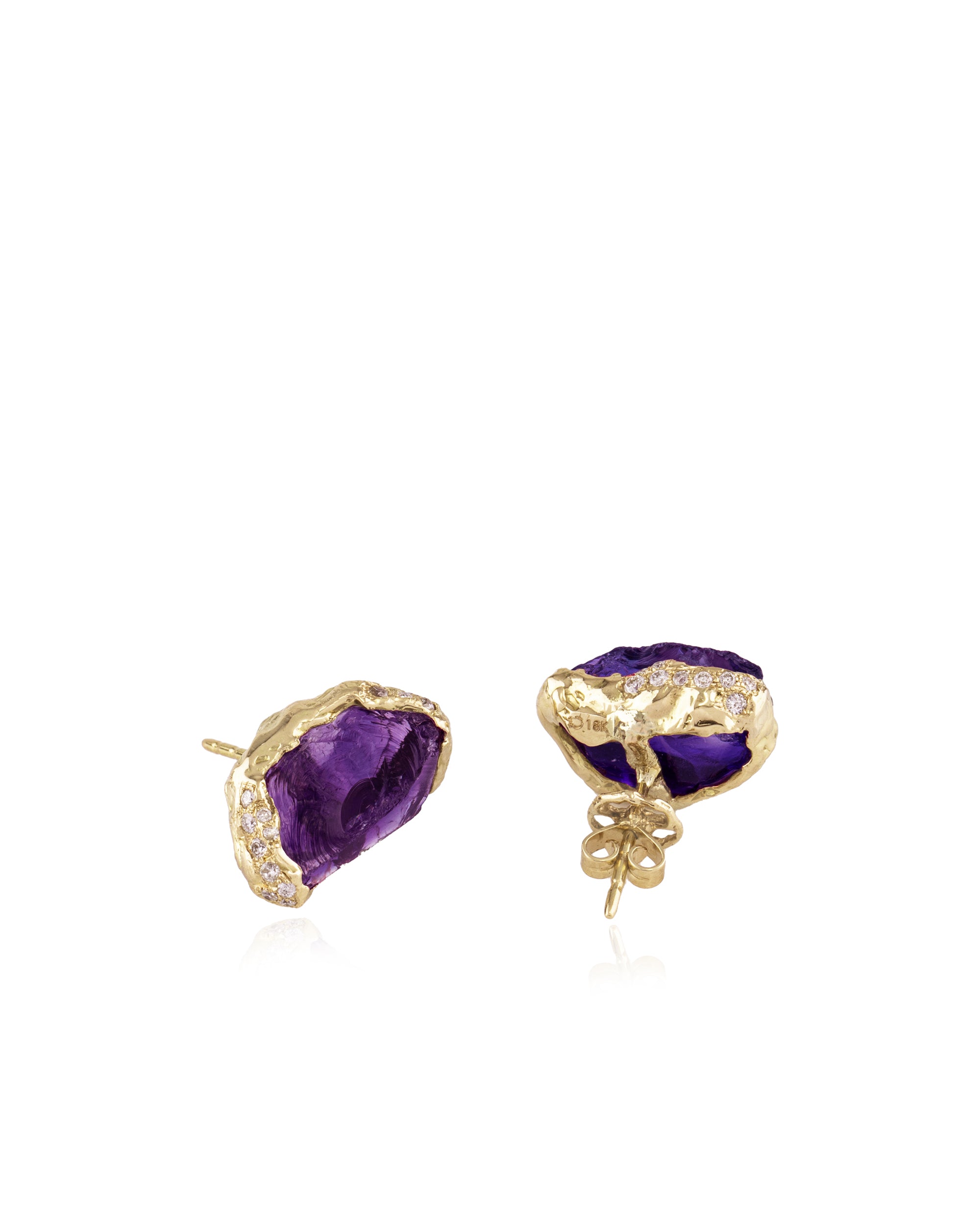 Angled product shot of the raw amethyst stud earrings displaying the post-and-butterfly backings and the textured 18K gold setting with diamond pave along the rim.