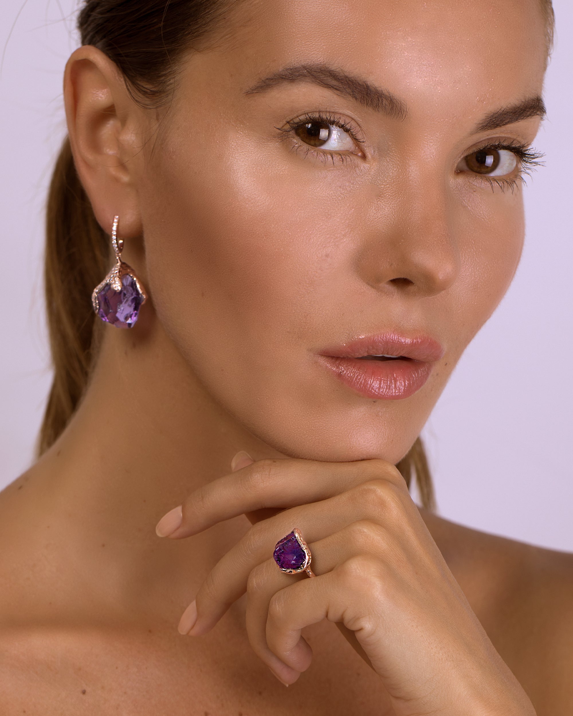 Model portrait showcasing a Natalie Dissel 18K yellow gold raw amethyst ring and matching raw gemstone drop earrings