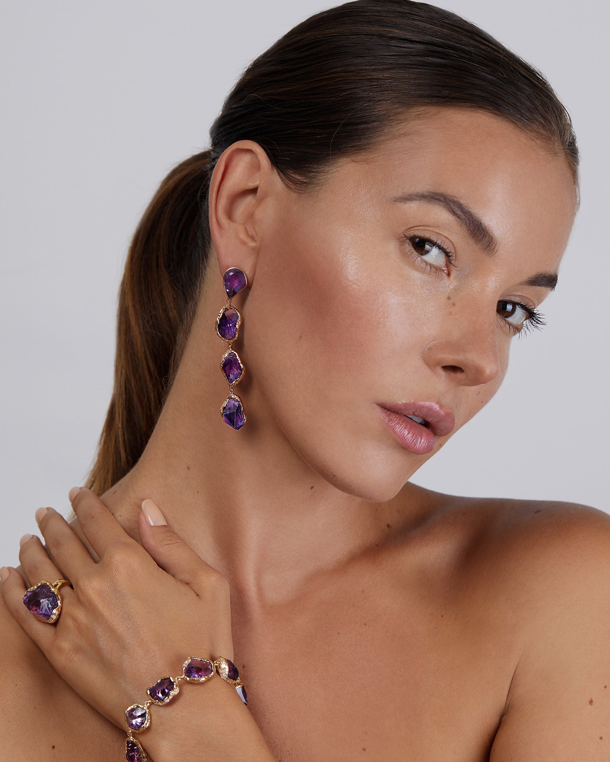 Model wearing Natalie Dissel 18K rose gold long raw Amethyst statement earrings, Rough Rocks collection, with matching ring and bracelet.