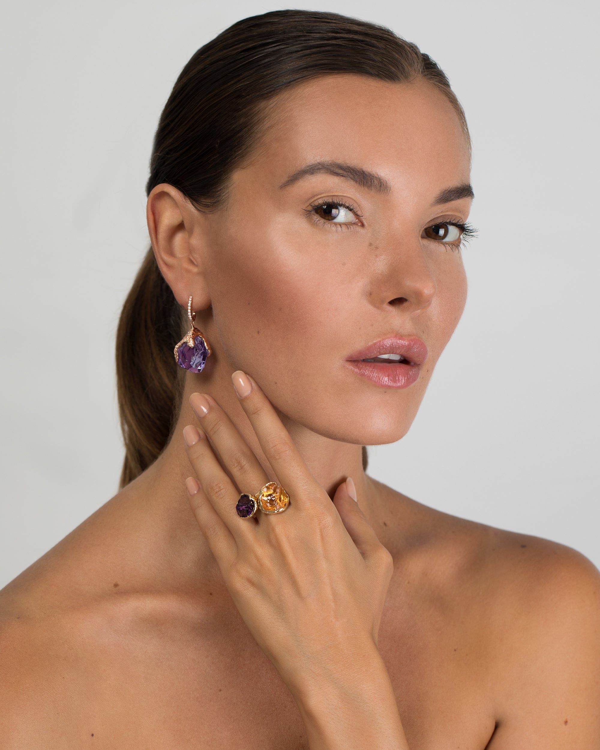 Model portrait wearing Natalie Dissel 18K rose gold raw Amethyst drop earrings with diamond details, styled with a raw gemstone ring.