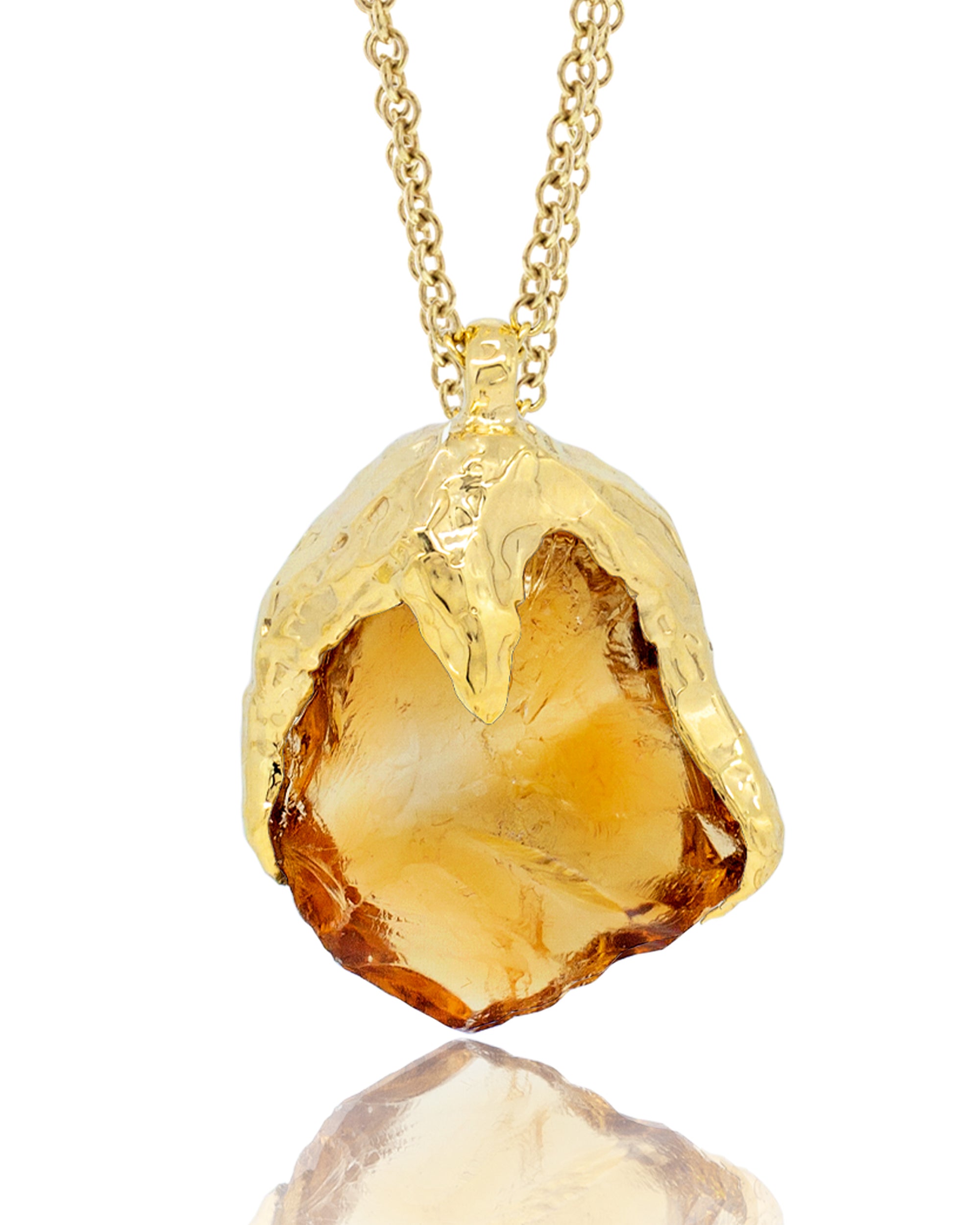 Close-up macro view of a raw, honey-yellow citrine gemstone pendant naturally capped in molten-textured 18K yellow gold, suspended from a gold chain.