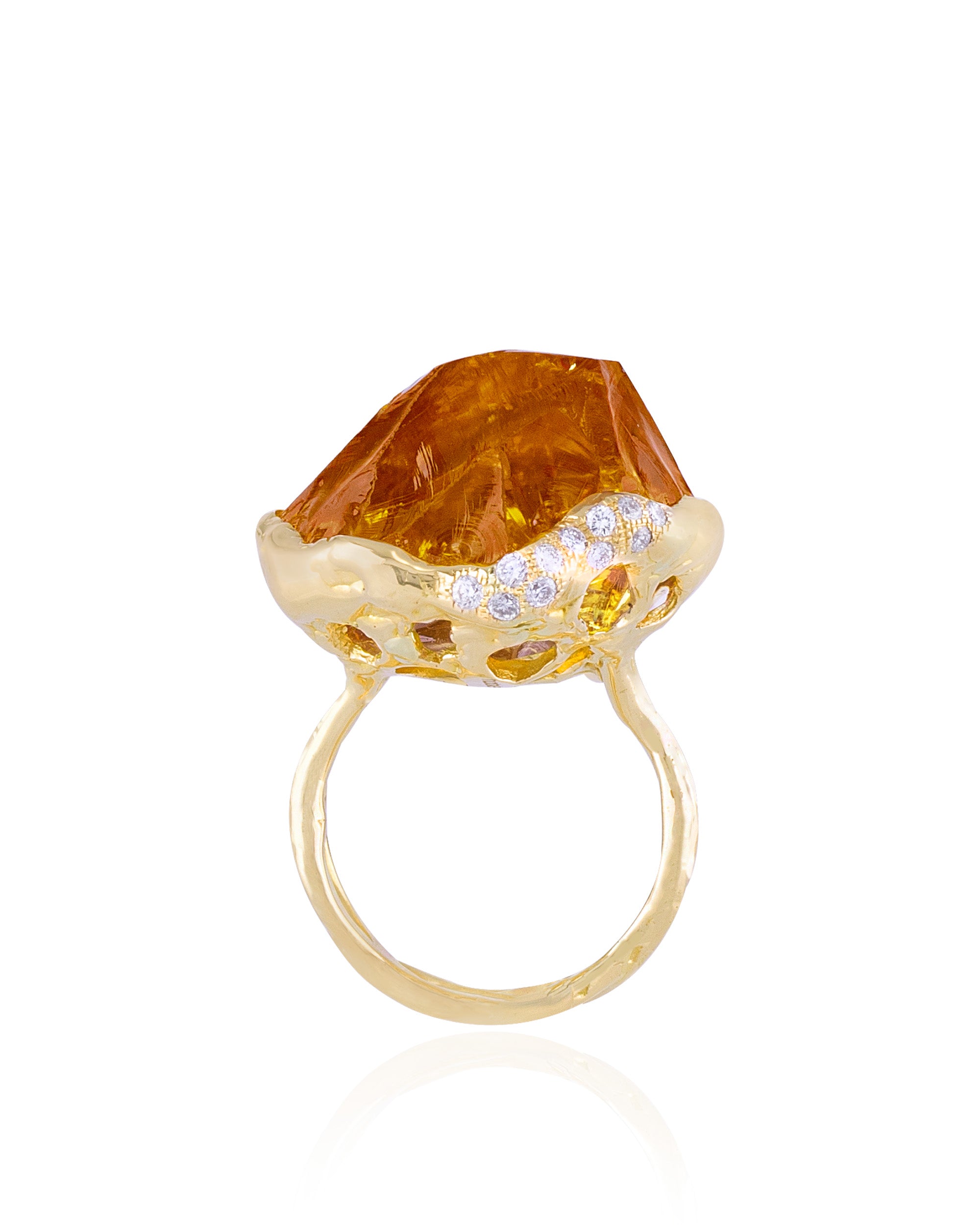 Frontal view of an 18K yellow gold statement ring displaying an elevated, raw-cut golden-yellow citrine gemstone surrounded by a textured bezel adorned with scattered pavé-set diamonds.