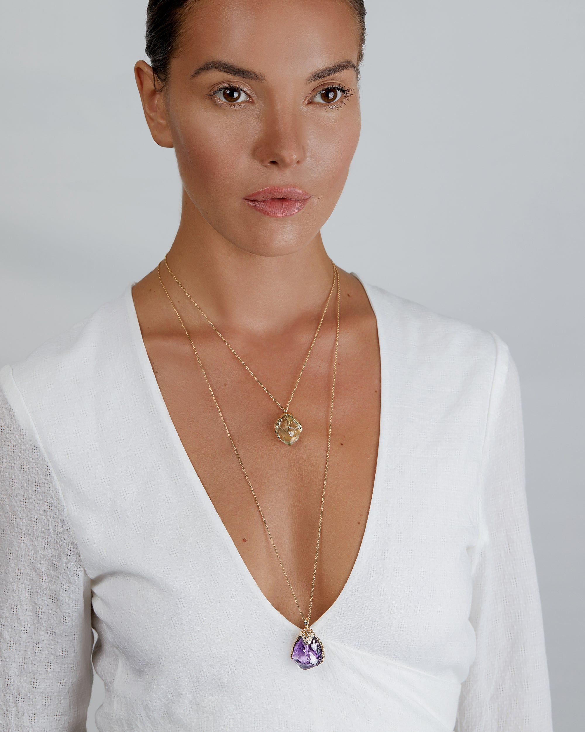 Model wearing Natalie Dissel 18K yellow gold raw Prasiolite pendant necklace layered with a long raw Amethyst pendant necklace, Gem Rocks collection.