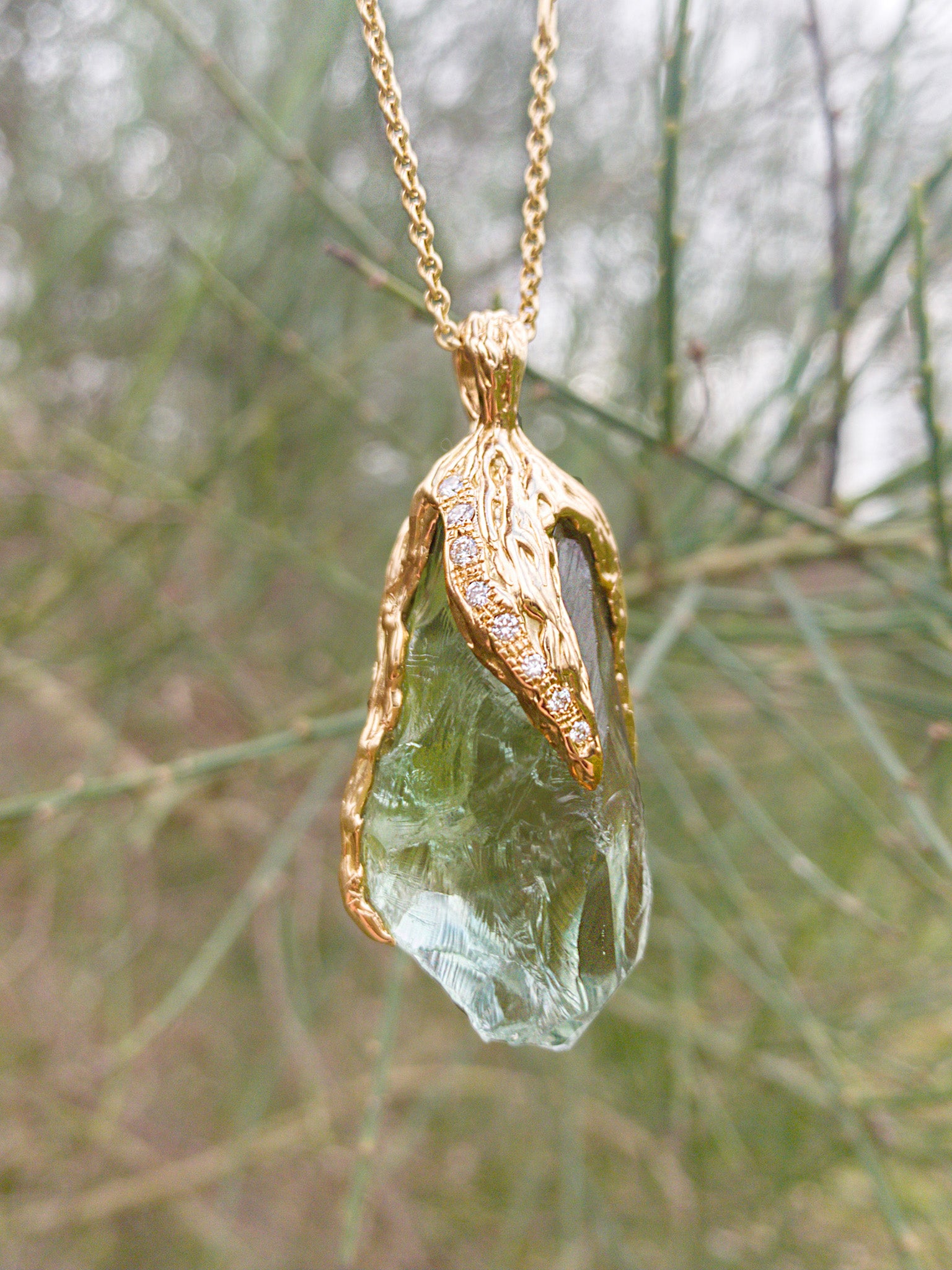 Close-up detail of Natalie Dissel 18K yellow gold pendant featuring a raw green Prasiolite crystal capped with textured gold and pavé diamonds, Rough Rocks collection.