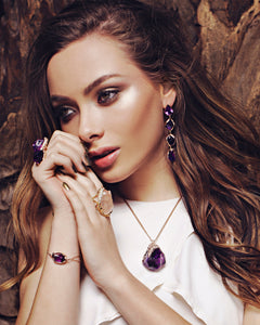 Model styled wearing the Natalie Dissel 18K yellow gold raw Rose Quartz ring alongside raw gemstone drop earrings, bracelet, and pendant.